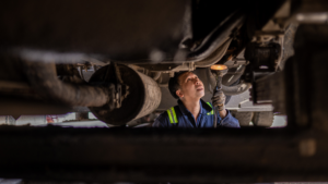 Mechanic inspecting vehicle equipment to support fuel management, maintenance planning, and long-term operational cost control.
